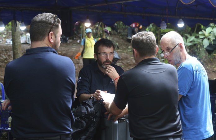Australian Federal Police and Defense Force personnel on Thursday, July 5, talk about extraction plans to get the 12 boys and their soccer coach out of the flooded cave. (AP Photo/Sakchai Lalit, File)