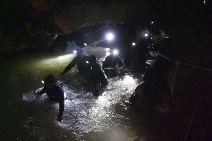 Thai rescue teams walk through rushing water inside the cave complex July 2. (Tham Luang Rescue Operation Center via AP, File)
