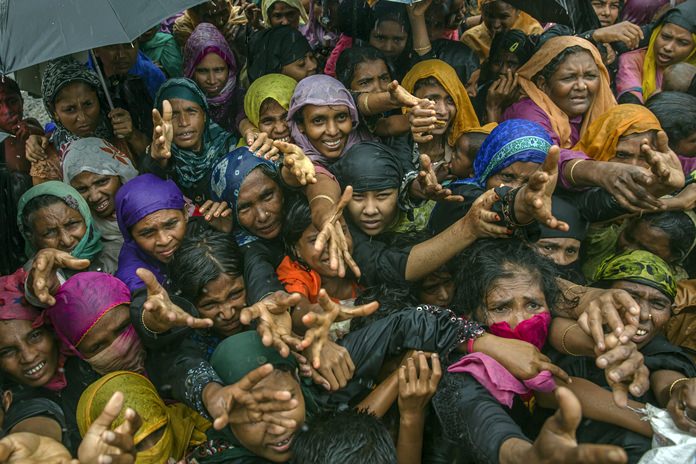 In this Sunday, Sept. 17, 2017, file photo, Rohingya Muslim women, who crossed over from Myanmar into Bangladesh, stretch their arms out to collect sanitary products distributed by aid agencies near Balukhali refugee camp, Bangladesh. Thailand’s military government is praising the U.S. State Department’s decision to upgrade the country in its annual report on efforts to fight human trafficking. (AP Photo/Dar Yasin, File)