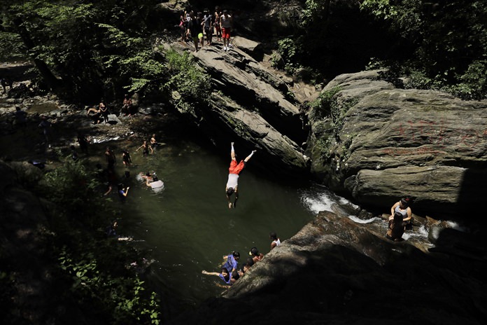 A man dives into the Devil’s Pool in Wissahickon Valley Park, Thursday, July 5, 2018, in Philadelphia. Record high temperatures have been logged over the past week around the world. (AP Photo/Matt Slocum)