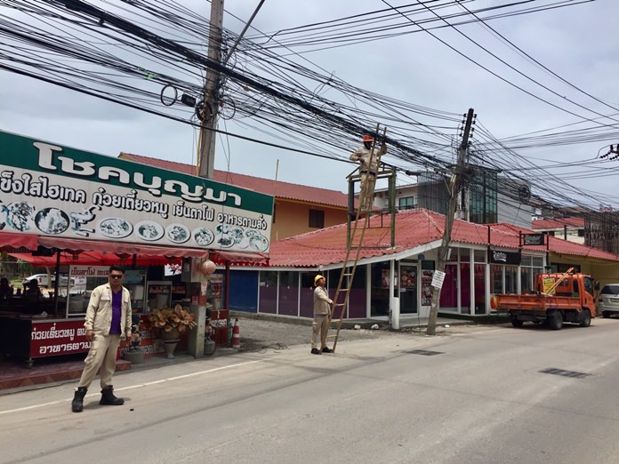 Workers from the Provincial Electricity Authority clean up messy jumbles of power and utility wires on Soi Khopai 4.