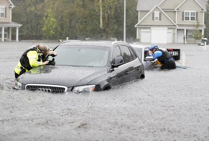 Members of the North Carolina Task Force urban search and rescue team check cars in a flooded neighborhood looking for residents who stayed behind as Florence continues to dump heavy rain in Fayetteville, N.C., Sunday, Sept. 16. (AP Photo/David Goldman)