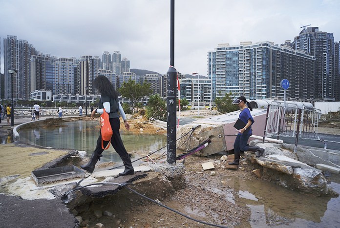 People walk past debris caused by Typhoon Mangkhut outside a housing estate on the waterfront in Hong Kong, Monday, Sept. 17. (AP Photo/Vincent Yu)