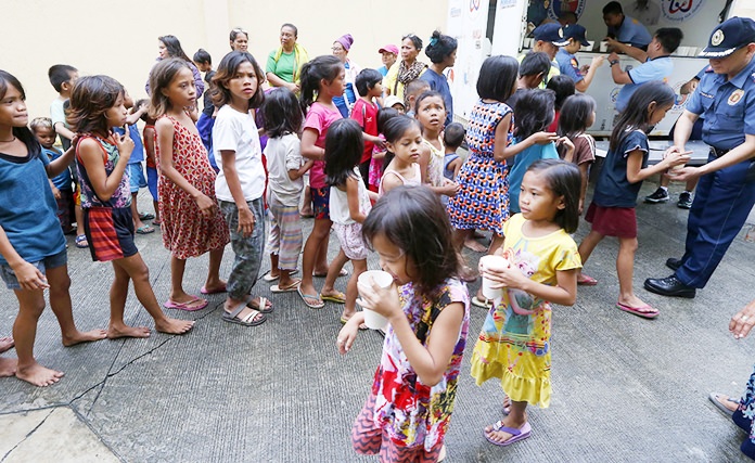 Manila police distribute rice porridge to residents living along the coastal community of Baseco as they evacuate at the onslaught of Typhoon Mangkhut which barreled into northeastern Philippines before dawn Saturday, Sept. 15. (AP Photo/Bullit Marquez)