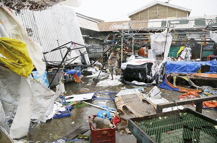 Residents walk along destroyed stalls at a public market due to strong winds Saturday, Sept. 15, as Typhoon Mangkhut barreled across Tuguegrao City in Cagayan province, northeastern Philippines. (AP Photo/Aaron Favila, File)