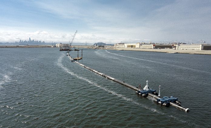 In this Monday, Aug. 27, 2018 photo provided by The Ocean Cleanup, a long floating boom that will be used to corral plastic litter in the Pacific Ocean is assembled in Alameda, Calif. (The Ocean Cleanup via AP)