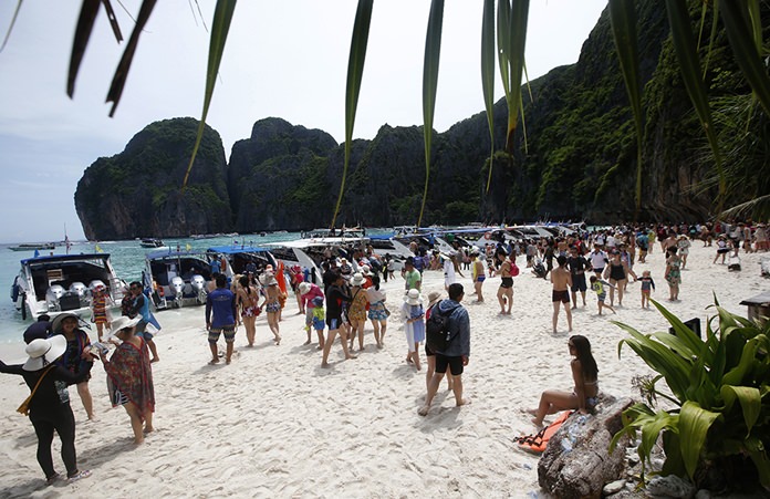 In this photo taken Thursday, May 31, 2018, tourists enjoy the beach on Maya Bay, Phi Phi Leh Island in Krabi province. Maya Bay will remain closed to tourists indefinitely until its ecosystem returns to its full condition, the Department of National Parks, Wildlife and Plant Conservation said in an announcement published on the Royal Gazette. (AP Photo/Sakchai Lalit)