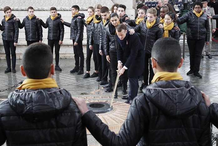 French President Emmanuel Macron re-lights the eternal flame at the Tomb of the Unknown Soldier during a commemoration ceremony for Armistice Day, 100 years after the end of the First World War at the Arc de Triomphe in Paris, Sunday, Nov. 11, 2018. (Benoit Tessier/Pool Photo via AP)