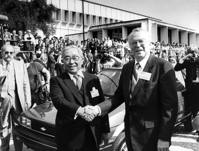 In this April 13, 1985 file photo, then Toyota Motor Corp. Chairman Eiji Toyoda (left) and then General Motors Corp. Chairman Roger B. Smith shake hands in front of a Chevrolet Nova at the new United Motor Manufacturing Inc. plant in Fremont, Calif. (AP photo/Paul Sakuma)