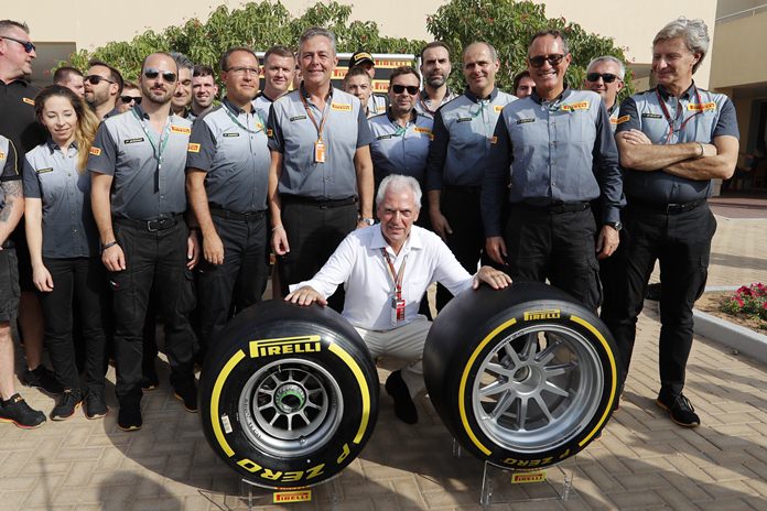 Pirelli CEO Marco Tronchetti Provera (center) poses with his staff behind the new Pirelli tyre ahead of the Emirates Formula One Grand Prix at the Yas Marina racetrack in Abu Dhabi, Sunday, Nov. 25. (AP Photo/Hassan Ammar)