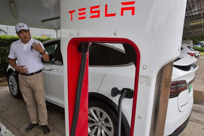 Shan Junhua chats about privacy near his white Tesla while charging it in Shanghai. (AP Photo/Ng Han Guan)