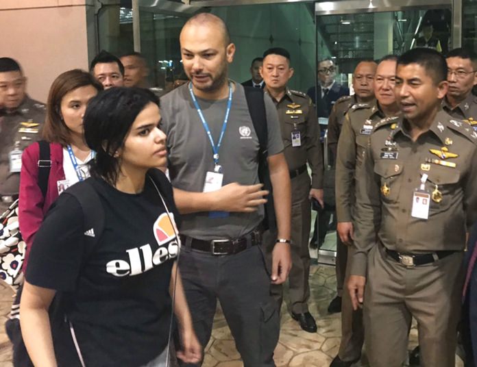 Saudi woman Rahaf Mohammed Alqunun, foreground walks by Chief of Immigration Police Maj. Gen. Surachate Hakparn, right, before leaving the Suvarnabhumi Airport in Bangkok Monday, Jan. 7. (Immigration police via AP)
