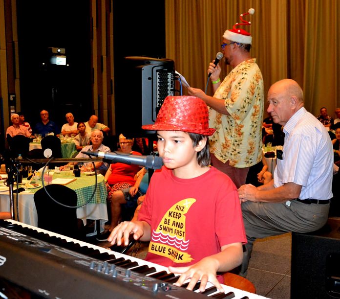 Ben Rudolf stands ready at the keyboard as Marcus Tristan (with microphone) prepares everyone to join in with the singing of Christmas Carols.