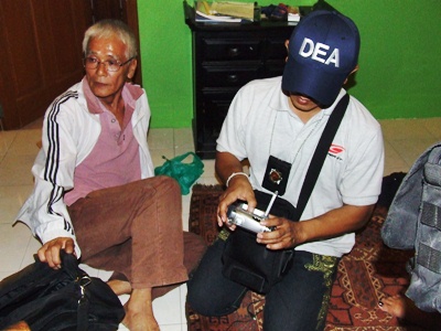 Police search Isao Handa’s (left) belongings after arresting him for allegedly abusing a 13-year-old boy.