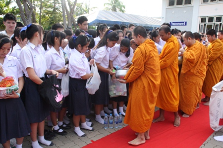 Singsamut students give alms to Buddhist monks at Sattahip Temple before presenting relief goods for flood victims to the Royal Thai Navy.