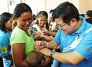 Deputy Mayor Verawat Khakhay (right) helps administer polio vaccine to area children.