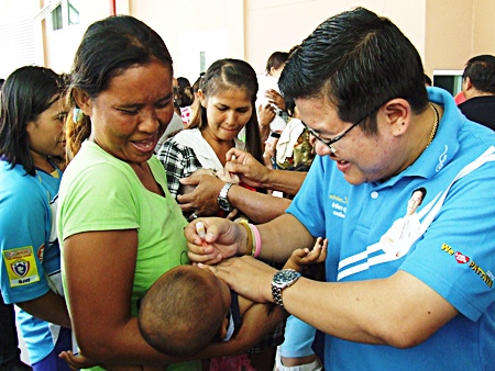 Deputy Mayor Verawat Khakhay (right) helps administer polio vaccine to area children.