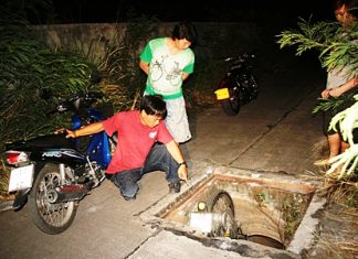 Rescuers arrive and after checking over the victim, begin to hoist the motorbike out of the drain.