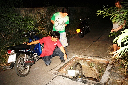 Rescuers arrive and after checking over the victim, begin to hoist the motorbike out of the drain.
