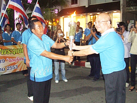 Wattana Chantanawaranon, Deputy Mayor of Pattaya City, receives the auspicious National Games torch from a representative of the Takhiantia Municipality on Monday, December 7 at Bali Hai Pier, Pattaya.