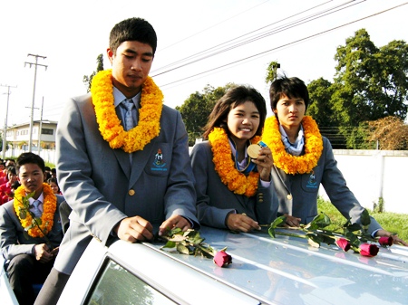 Noppakao Poonpat, flanked by fellow student teammates from the 2010 Asian Games, shows off her sailing gold medal in an open topped parade around Sattahip, Monday, November 29. 