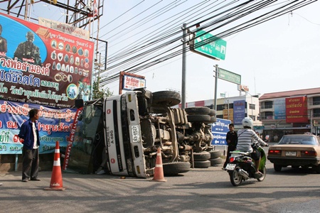 Driver Kan Kanhawong (left) stands next to the overturned cement truck he crashed in Sattahip.