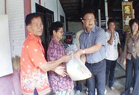 Deputy Mayor Wutisak Rermkitkarn, centre right, hands over relief supplies to Naklua resident Viang Saengthong, left, after the latter’s house was badly damaged during a Feb. 15 rainstorm.