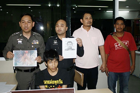 Police, shown here holding photos of two more suspects, have arrested Santhan Kammongkol (seated) for his involvement in the robbery of a 7-Eleven. 