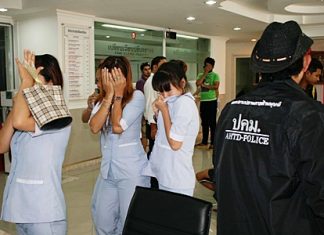 Staff at the clinic hide their faces as they are led away for questioning by the police.