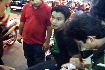 Somsong Imsin is arrested by police officers outside his grilled chicken stall near the Marine Hotel in south Pattaya.
