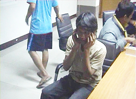 Dechsak Saejang awaits questioning by police officers following his arrest.