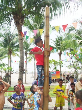 With the help of his friends, will this youngster reach the 500 baht prize at the top of the greased pole?