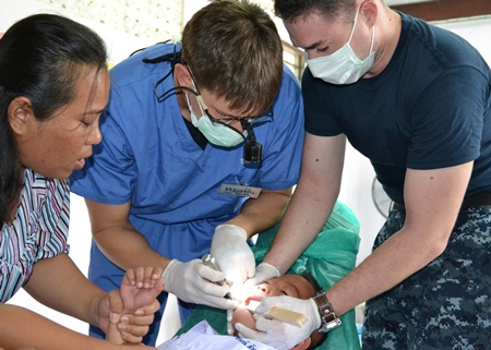 Ban Chang (May 12, 2011) - Hospital Corpsman 2nd Class Jared Myers (right), attached to Commander Task Force 73, Singapore, assists Lt. Michael Syamken, attached to USS Tortuga (LSD 46), extract an infected tooth from a young Thai dental patient during the Medical Civic Action Program (MEDCAP) at the Somboon Ranaram School. (U.S. Navy photo by Mass Communication Specialist 1st Class Jose Lopez, Jr.)