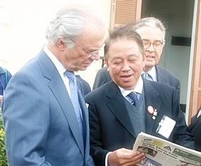 Sutham Phanthusak, commissioner of the National Scout Organization of Thailand, shows King Carl VI Gustav of Sweden our front page when we featured him visiting their Majesties the King and Queen of Thailand to say thank you for help for the tsunami victims. The man in the background is the chairman of the World Scout Foundation, Dr. Eberhard Von Koerber. The pic was taken at a Scout camp outside Rome April 22, 2005.