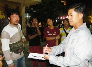 Krit Suwanpiyawong (left) is taken into custody by Maj. Wasu Sangsuksai (right), chief of Pattaya City Hall’s regulatory enforcement department.