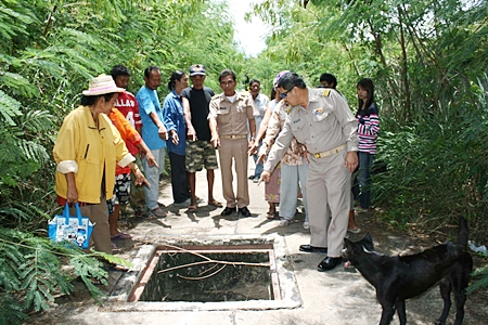 Villagers and officials point to one of the many dangerous uncovered drains in the road after thieves had stolen the cover. 