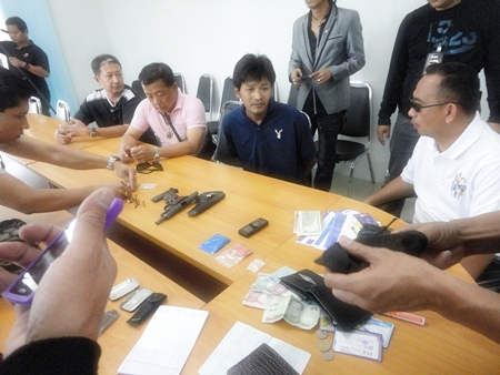 Saksit Suwadit (seated center) is brought in for questioning after police nailed him in a sting operation. 