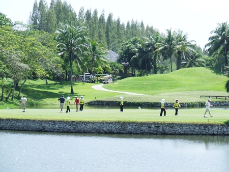 Golfers take on the challenging island green signature hole.