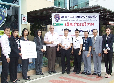 Neera Sirisamphan (3rd left) and Steve Graham (5th left) present their respective donations to Pol. Col. Choosak Panusamporn commander of Chonburi Immigration for their flood relief efforts.