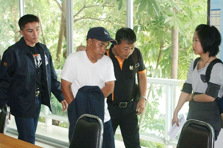 “I’m innocent.”  Officials lead away Prayong Thongdeewong after charging him with two acts of vandalism that cost the city as much as 30 million baht each. 