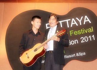 Winner of the 2011 Guitar Festival competition, Chinnawat Themkumkwun (left) accepts his prize guitar from Deputy Mayor of Pattaya, Ronnakit Ekasing.