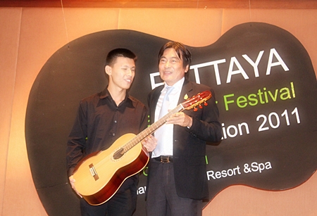 Winner of the 2011 Guitar Festival competition, Chinnawat Themkumkwun (left) accepts his prize guitar from Deputy Mayor of Pattaya, Ronnakit Ekasing.