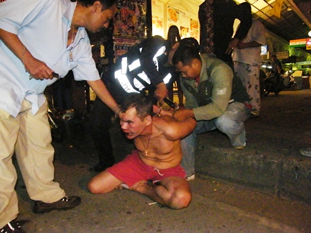 Police and motorcycle taxi drivers wrestle the crazed Russian and put him in handcuffs. 