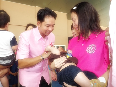 Mayor Itthiphol Kunplome helps a mother give her child some polio vaccine drops. 