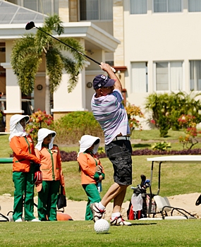 Caddies look on as another shot splits the fairway.