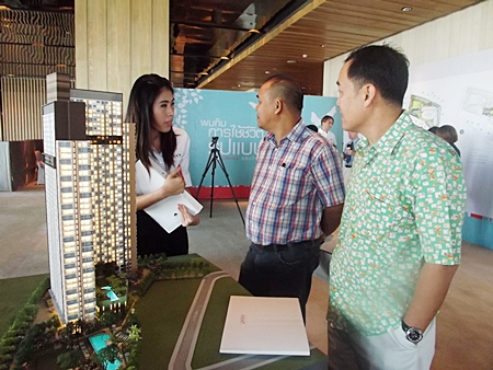 Interested buyers and a Raimon Land sales representative stand next to a scale model of the Unixx project at an open day held at the Hilton Hotel Pattaya on Saturday, Dec. 10.
