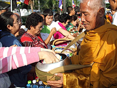 A Buddhist monk receives alms from citizens along Jomtien Beach Road in the early morning hours of Jan 1, 2012. Some roads were temporarily closed in Pattaya, Naklua and Jomtien at the start of the year, as Thais lined the thoroughfares to welcome in the New Year by making merit, offering alms to monks and praying for a happy, healthy and prosperous 2012 for themselves and for everyone throughout the world.