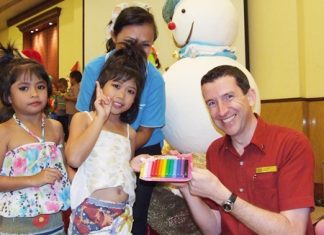 Michael Delargy (right), Sheraton Pattaya Resort general manager, hands out Christmas gifts to youngsters from the Seaton Center.