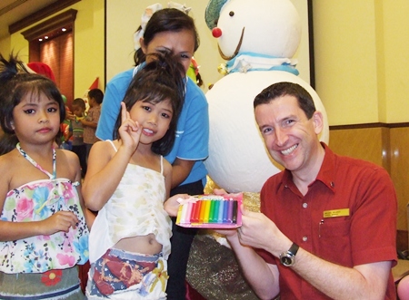 Michael Delargy (right), Sheraton Pattaya Resort general manager, hands out Christmas gifts to youngsters from the Seaton Center.