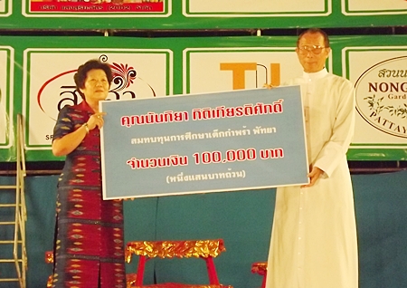 Feiyan troupe organizer Nanthiya Kittikiettisak presents orphanage Director Rev. Veera Phangrak with a donation of 100,000 baht.